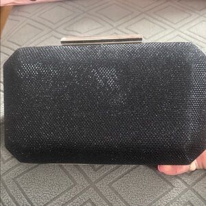 Nina “Hard Clutch Crossbody features a hard-shell design sparkly finish.